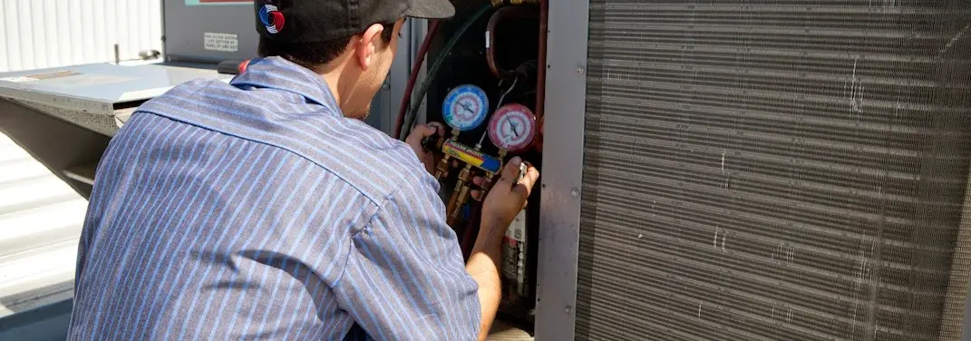 HVAC technician servicing a condenser unit in Hastings